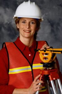 Accomplished surveyor proudly holding her theodolite, a symbol of her dedication and expertise, celebrating a successful graduation and bright future in the field of surveying.