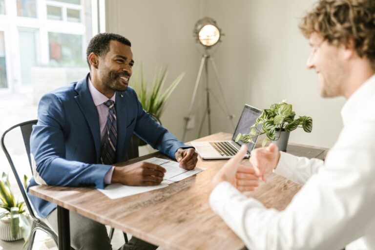 Engaged discussion on Title Insurance: Two individuals deliberating the vital protection it offers to property owners and lenders, safeguarding against disputes, claims, and potential financial liabilities related to the property's history and ensuring peace of mind.